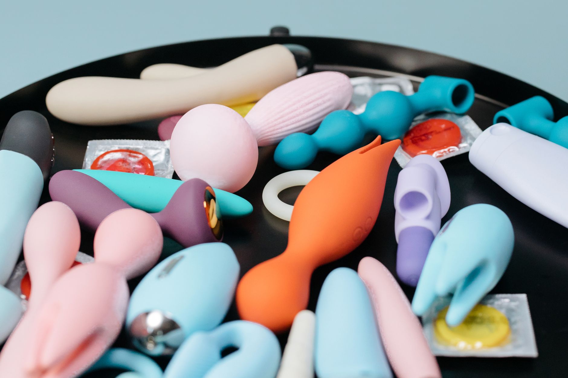 A vibrant collection of various adult toys on a black surface, showcasing diverse designs and colors.
