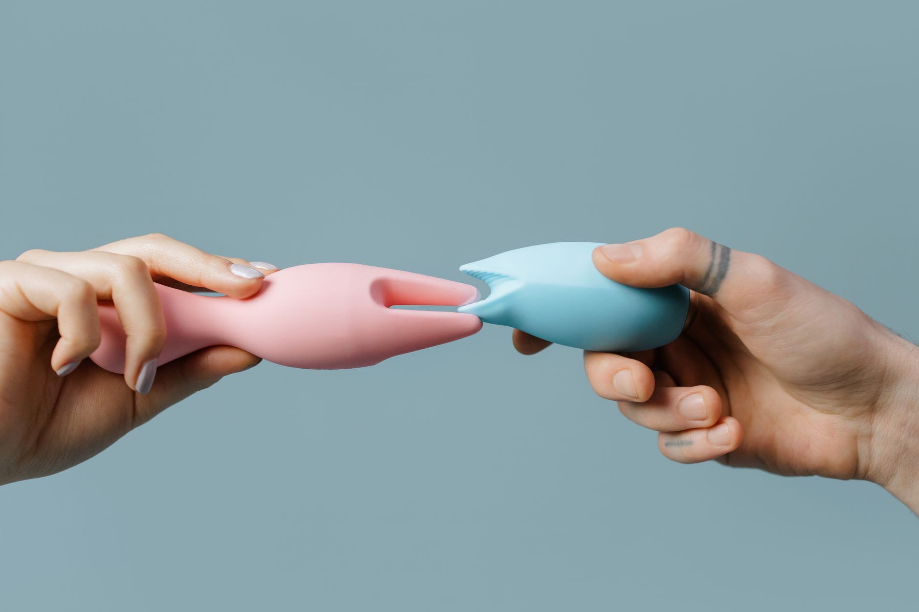Hands holding pastel-colored silicone toys in various shapes