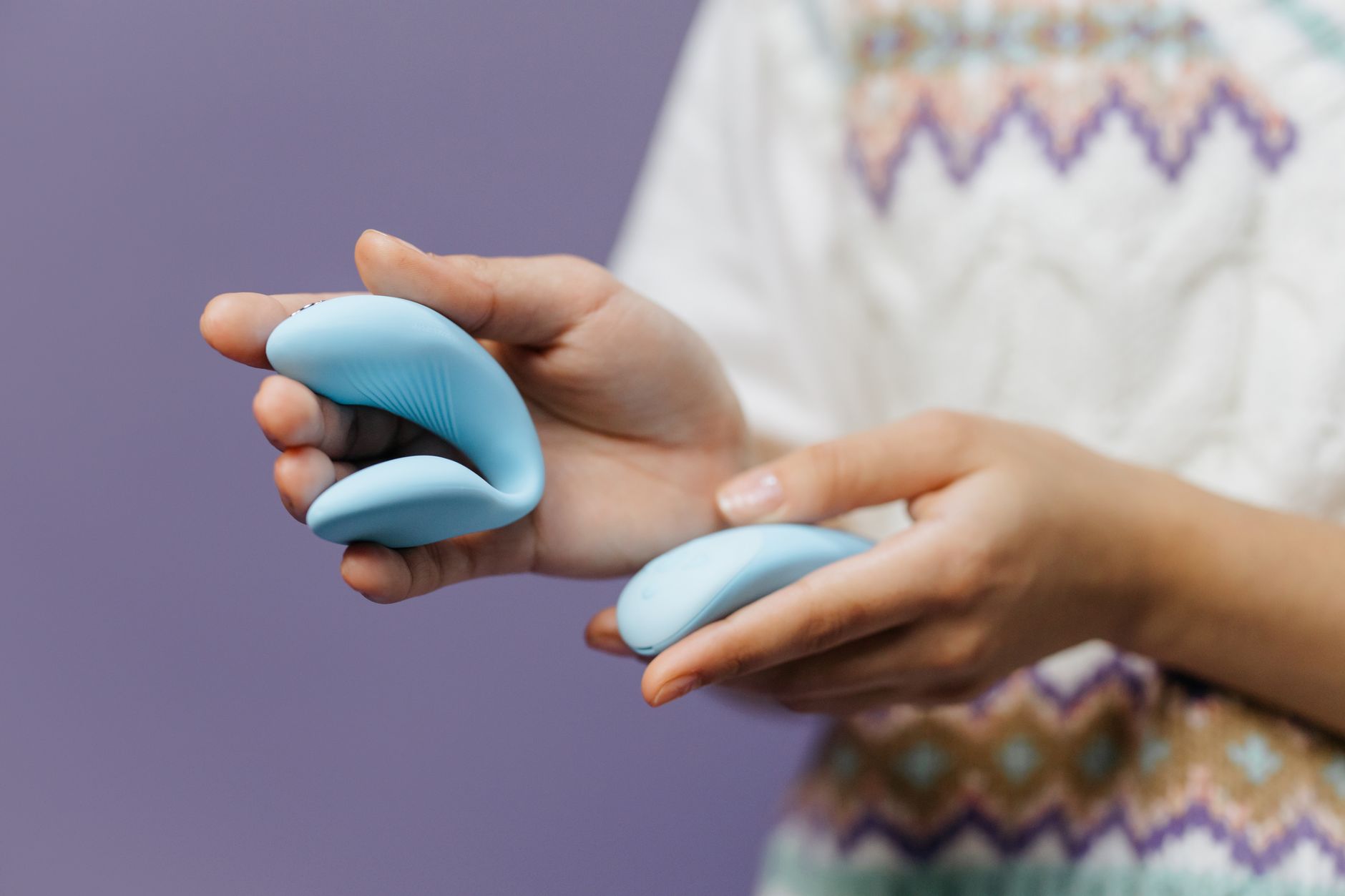 A close-up of hands exploring gentle touch with a sleek modern vibrator