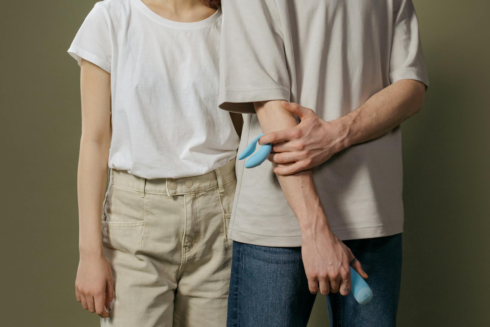 A couple holding a blue vibrator together, exploring intimate pleasure with confidence